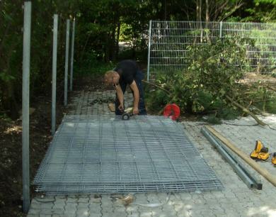 Hegnsstolper er faststbt, panelhegn-sektioner tilpasses og monteres.