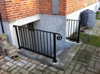 Smedejernsgelnder opbygget i samme stil som hovedtrappe gelnder og sammensvejst i massiv smedejern og monteret p klder nedgangstrappe i beton.