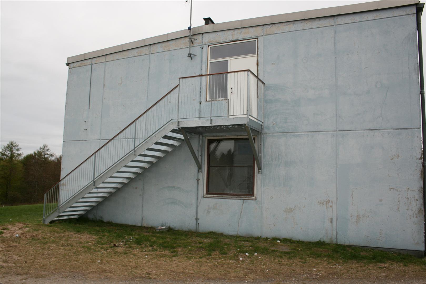 Ligeløbstrappe med repos, monteret direkte på beton-facade.