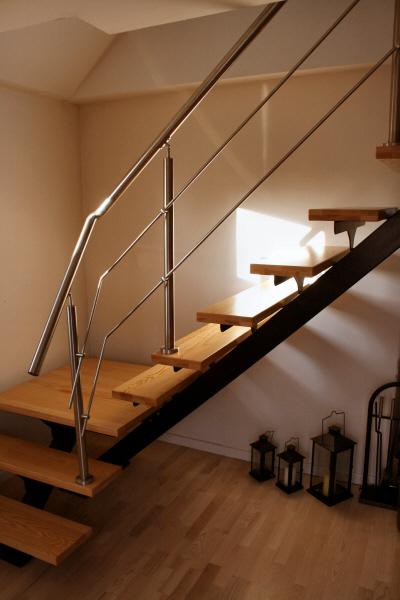 Indvendigt stålgelænder på trappetrin af ask : Opsadlet indendørs ståltrappe m. repos. Gelænder en side.